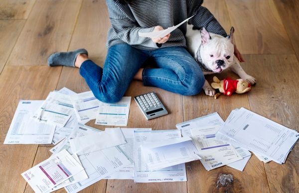 A woman reviewing invoices on the floor next to a dog 