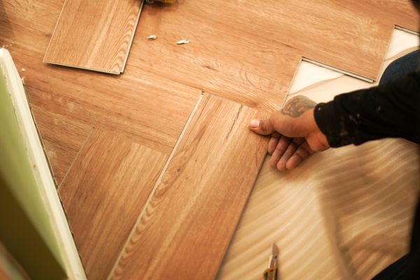A person installing vinyl wood plank flooring 