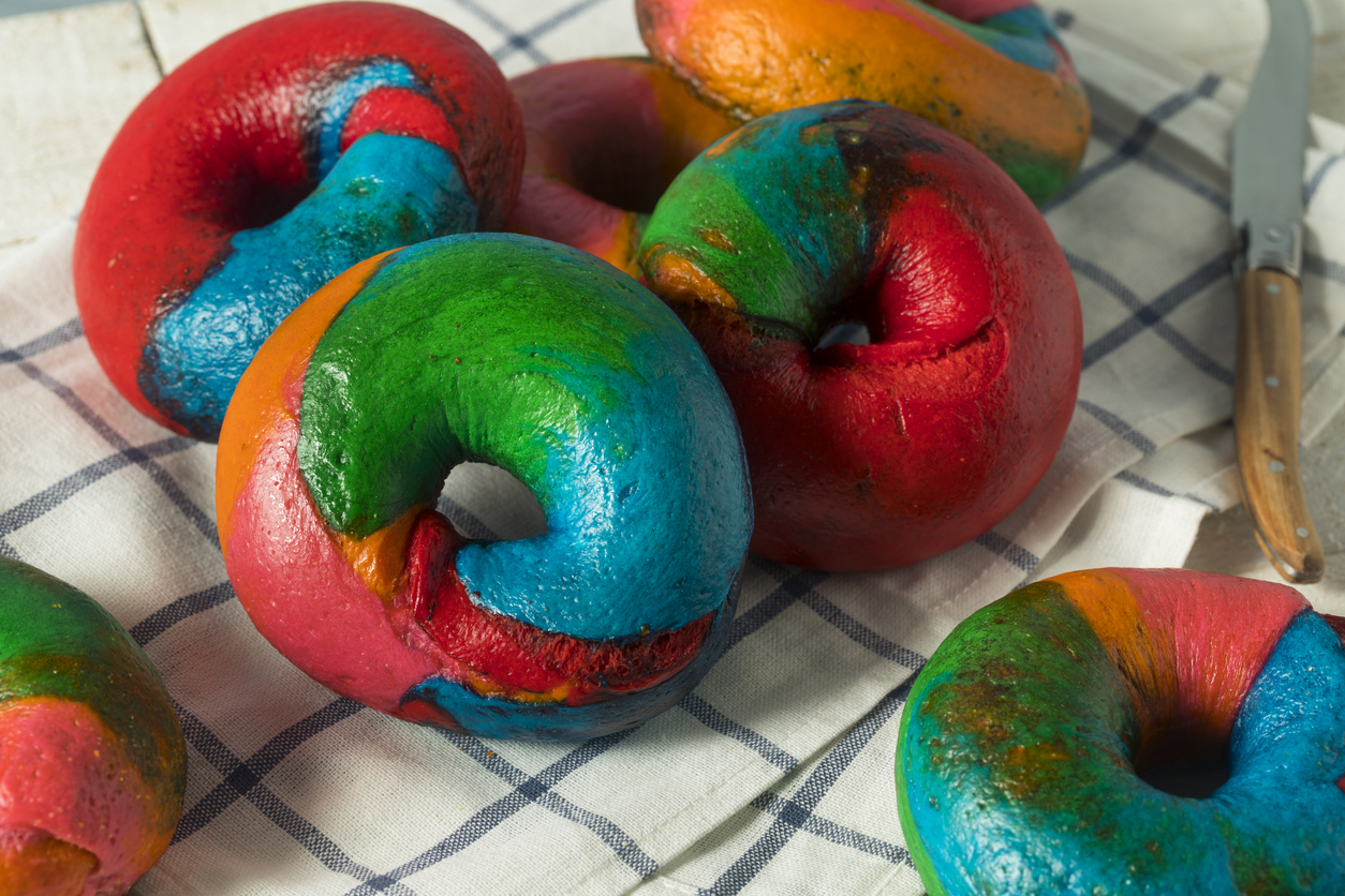 several rainbow bagels laid out on a gingham cloth