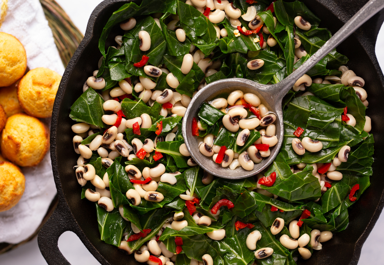 a cast-iron skillet full of black-eyed peas and collard greens
