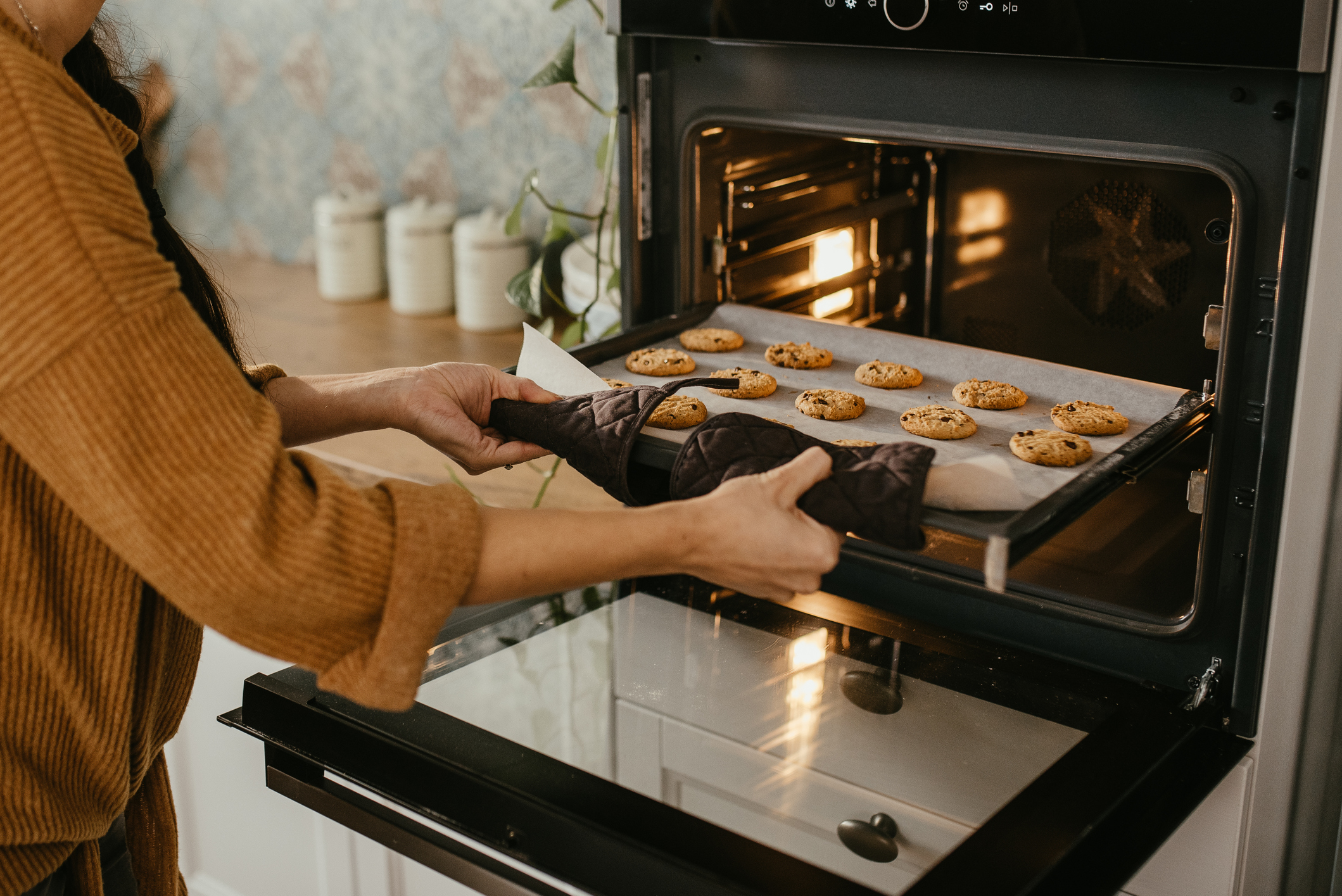pulling a tray of cookies out of a wall oven