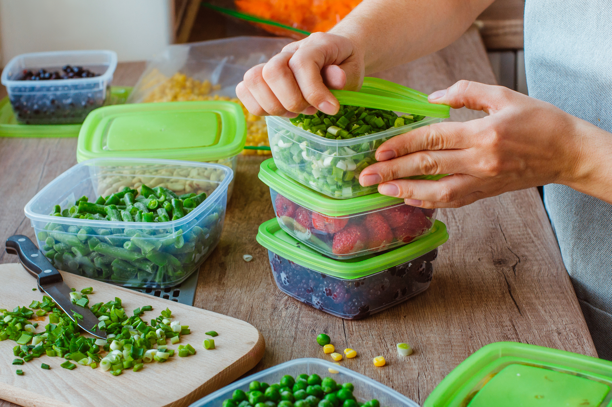 adding food to storage containers for meal prep