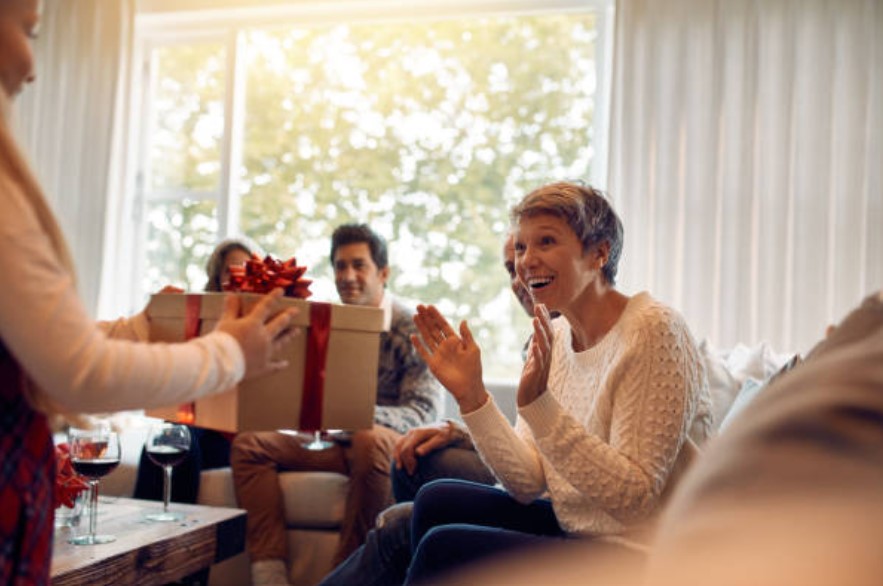 woman sitting in living room receiving gift 