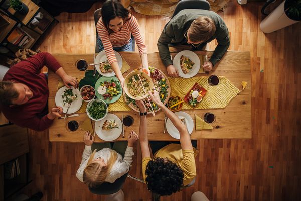 iStock Credit: South_agency An overhead view of friends enjoying dinner