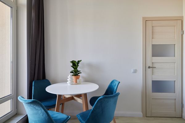 A small dining area with a modern dining set with blue chairs 