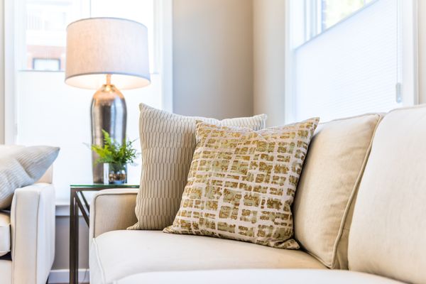 A close-up of a beige sofa with multi-colored throws 