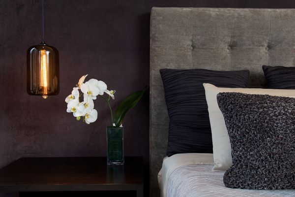 A black modern bedroom featuring orchids and a pendant light 