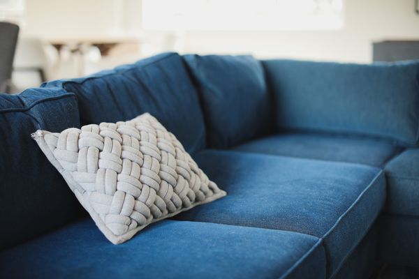 A blue microfiber sofa with a white toss pillow 