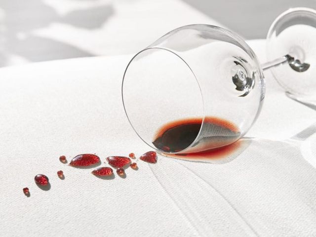 Close view of a glass of wine being spilled on a white sofa with performance fabric