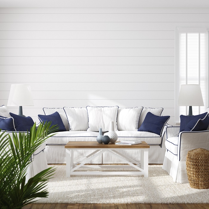 Bright living room with natural light focused on a white couch and arm chairs with blue and white pillows.
