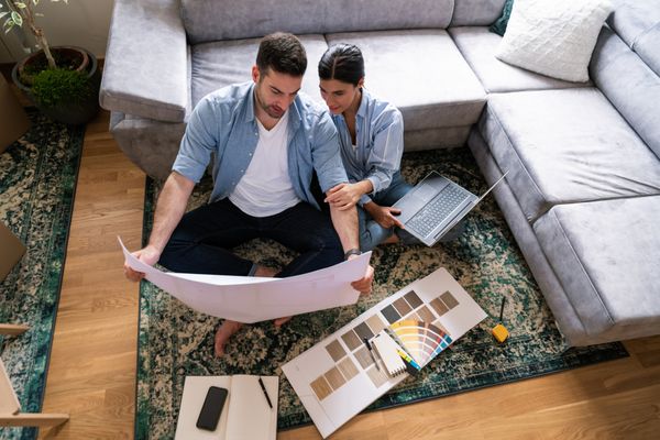 A man and a woman on the floor comparing color swatches