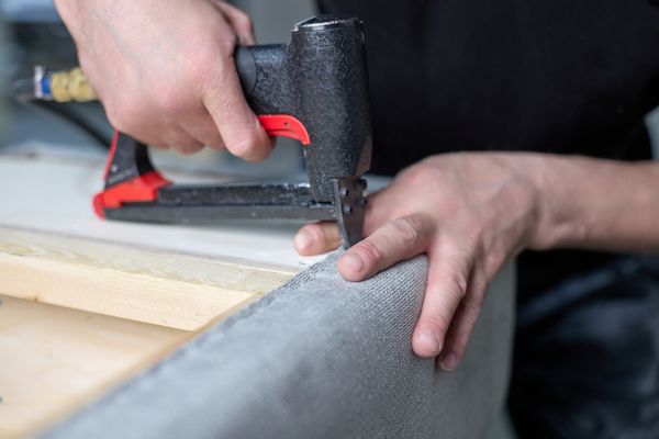A sofa craftsperson stapling upholstery to a sofa 