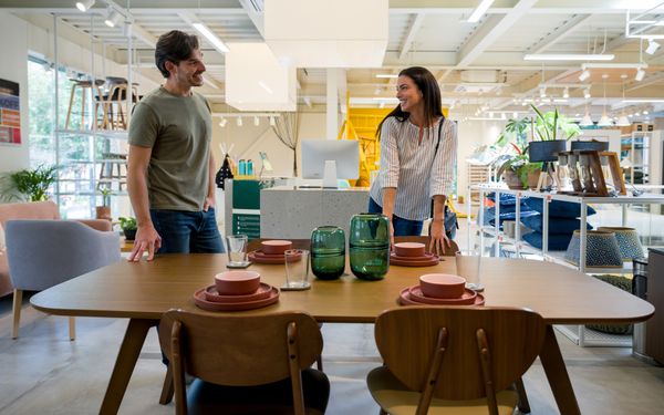 iStock Credit: andresr A smiling man and woman inspect a dining room set in a store