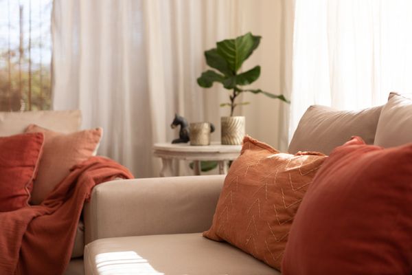 A close-up of a light brown sofa with earth-tone décor and bedding 