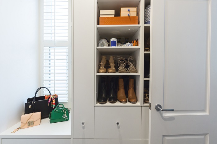 Shelves with shoes and other accessories next to a closet. 