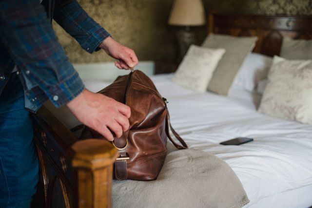 person reaching into duffle bag on bed