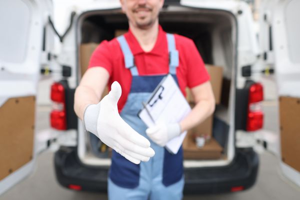 A deliveryman with white gloves extending his hand