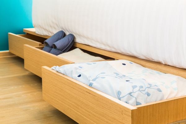 Open storage bed drawers containing bedding and slippers 