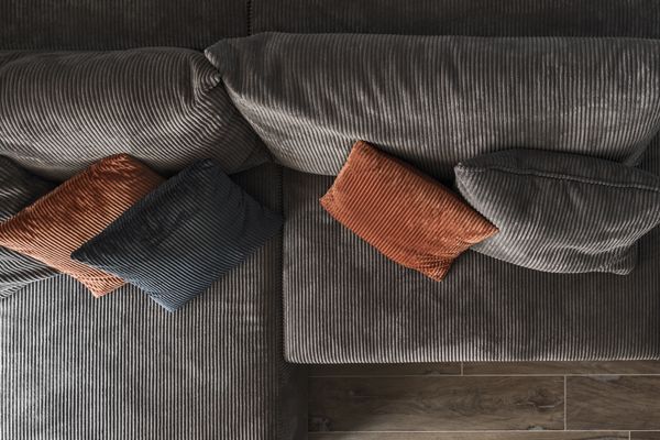 An overhead view of a gray corduroy sofa with brown and black pillows 