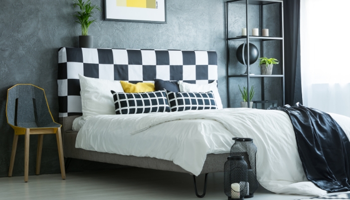 A stylish chair next to a bed in place of a nightstand