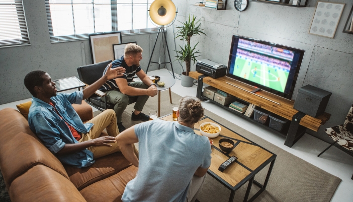 Friends watching football on a comfy sofa and chair