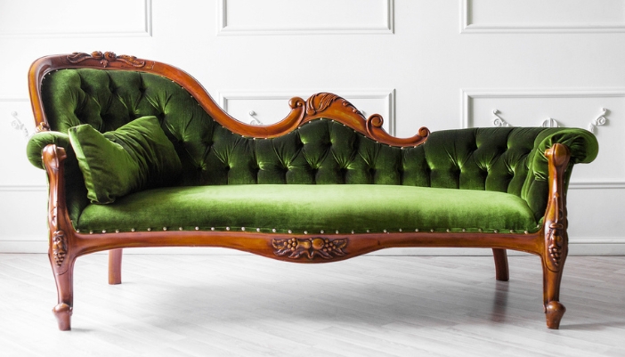 An art nouveau resting couch with bright green fabric and wooden accents.
