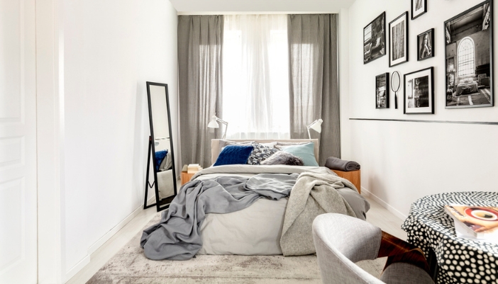 A small bedroom with a full bed, lots of wall art, and a small table in the corner.
