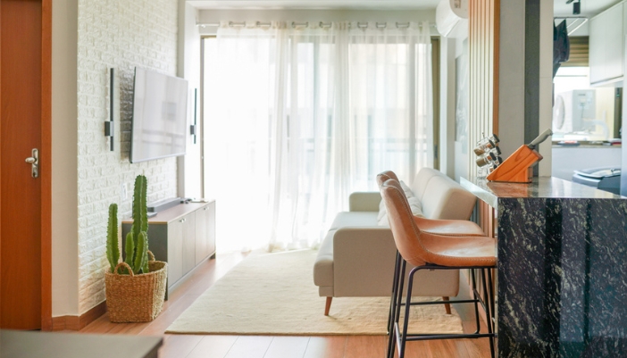 A brightly lit living room with a white couch and a breakfast bar.