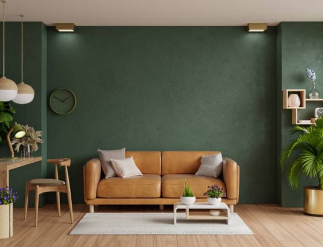 front view of a modern earthy-toned living room with dark green walls, light wood decor, and a light brown/orange leather sofa centered in the middle