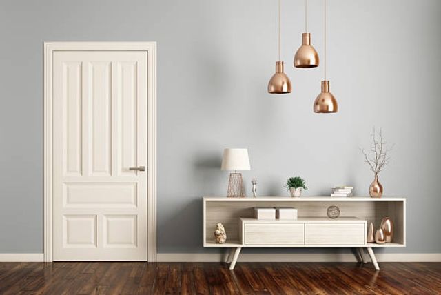 front view of an entryway with a light blue wall, white door, and white entryway cabinet styled with miscellaneous items