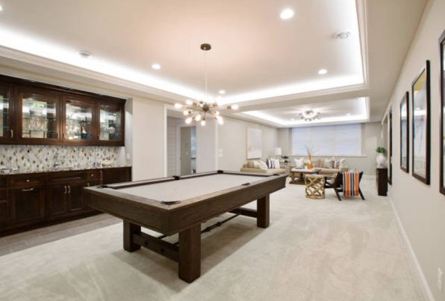 view of a large bright billiards room with a built in bar and pool table in the foreground and a small seating area in the background