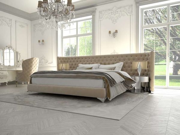 front view of a French provincial luxury bedroom, with a large upholstered headboard, crystal chandelier, and white ornate walls 