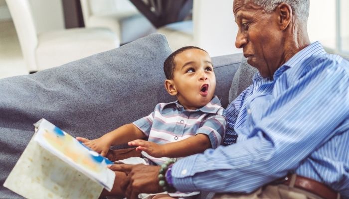 Grandfather and grandson reading a book on couch