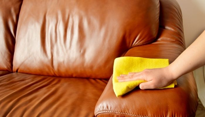 hand wiping down leather couch