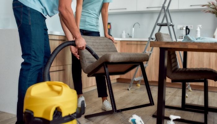 couple vacuuming upholstered chairs