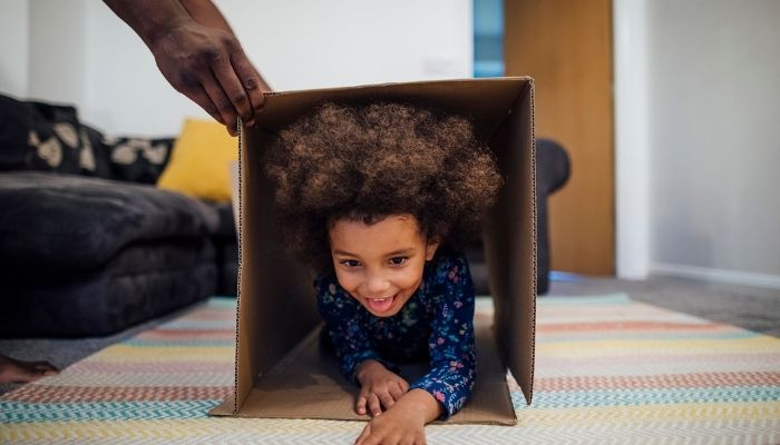 young boy crawling through cardboard box