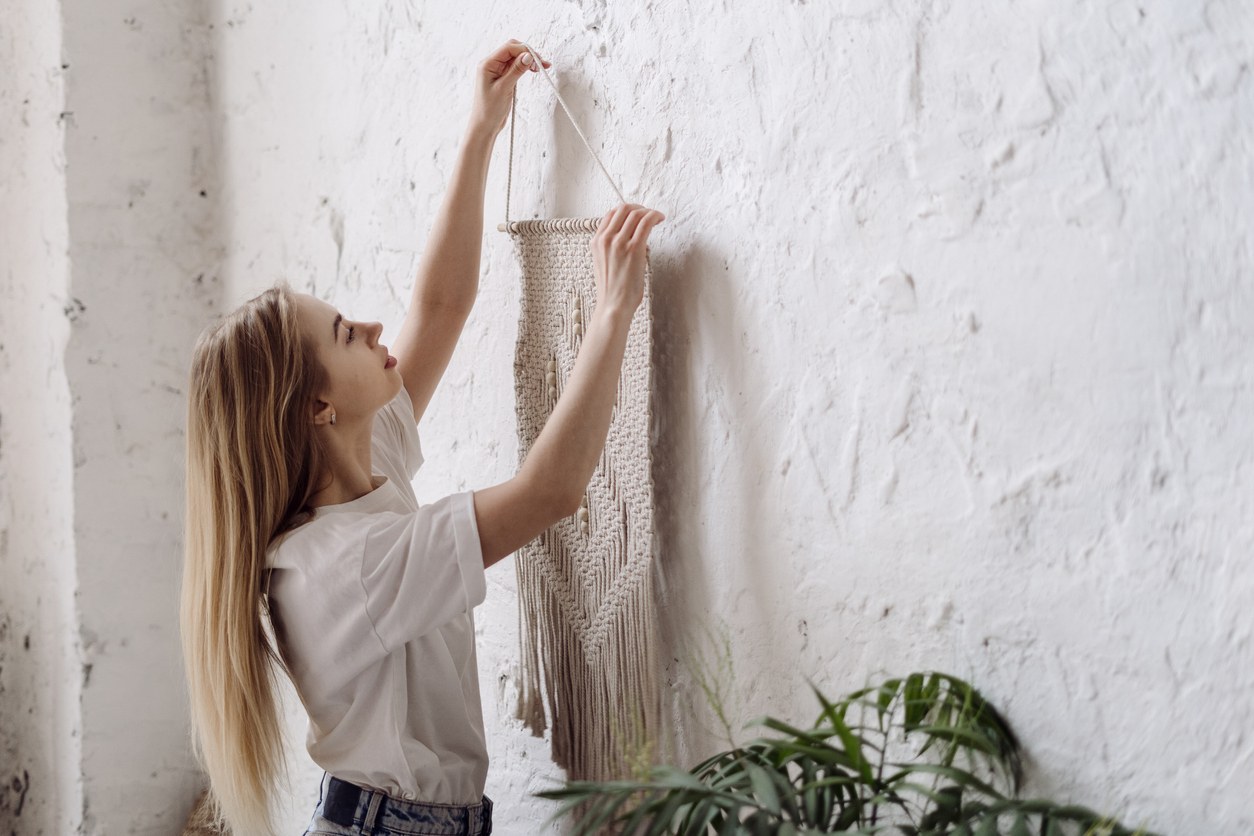 girl hanging up wall art in her bedroom