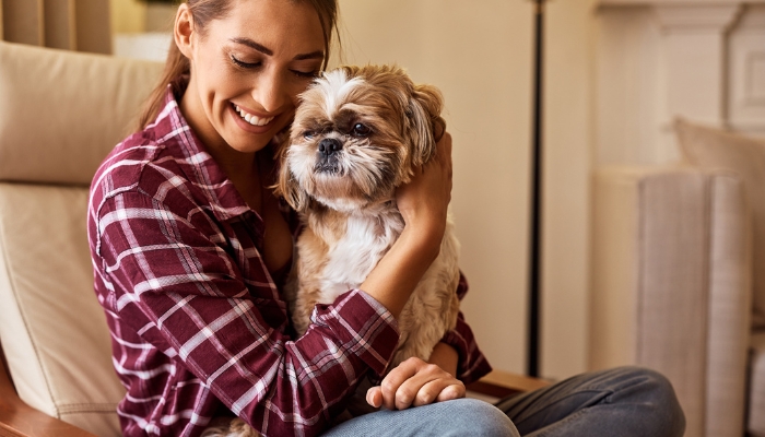 Woman cuddling dog while in chair