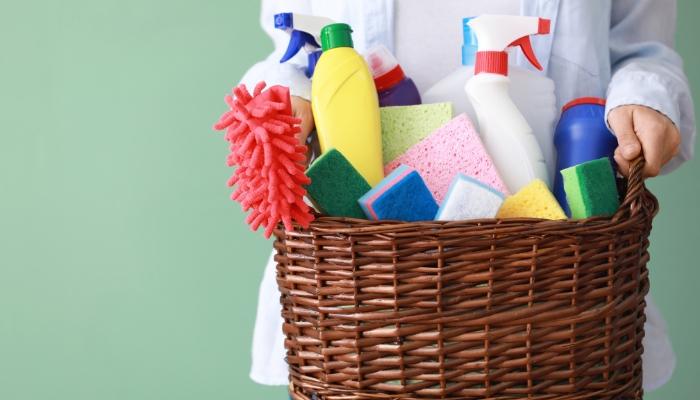Closeup of person holding a basket of cleaning supplies