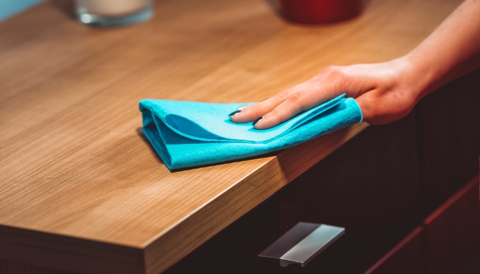 Close of hand wiping down wood desk