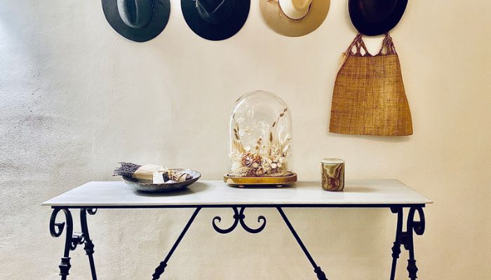 Modern iron entryway table with hats hanging above and dried flowers on the table