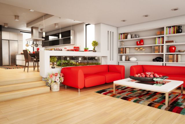 front view of a modern living room with a bright red sofa and an open concept kitchen in the background