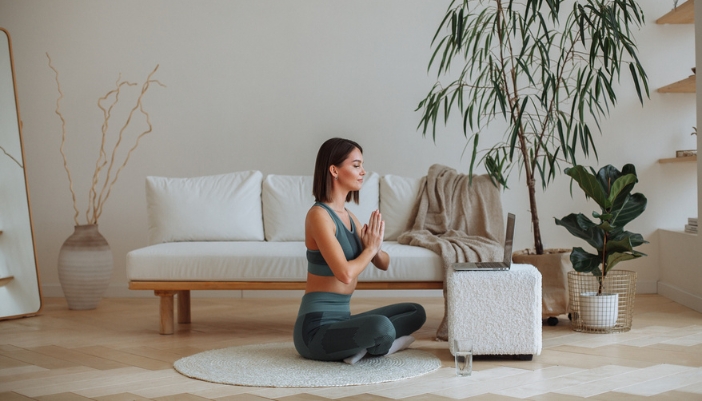 A woman sits in her living room and watches meditation exercises at home.