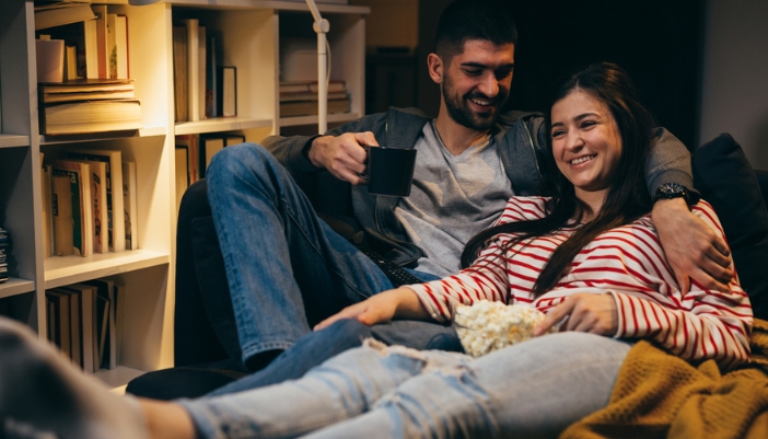 A couple reclines on their furniture at home.