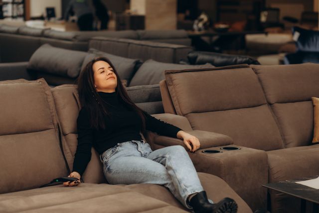 front view of a woman trying out a reclining sofa in a furniture store