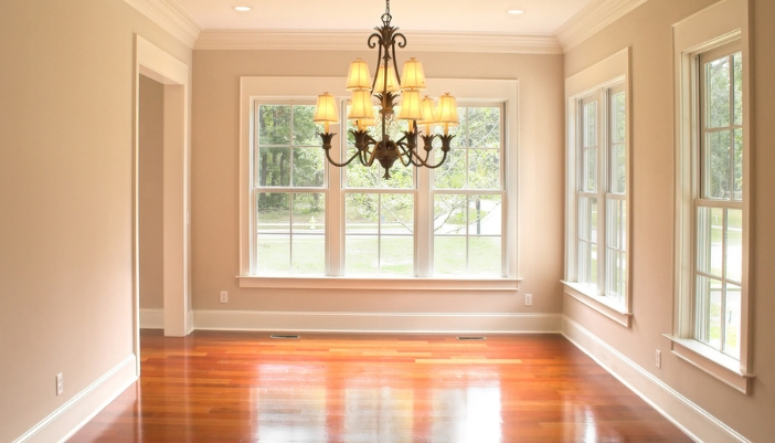 An empty dining room with wooden floors and a vintage chandelier. 