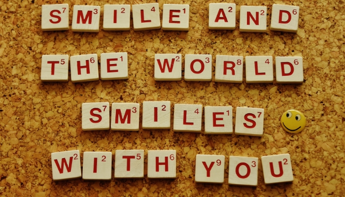 Affirmative saying spelled out with Scrabble tiles on a wooden board