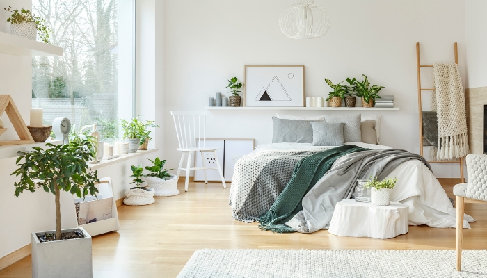 A white, bright bedroom with lots of greenery and open space 