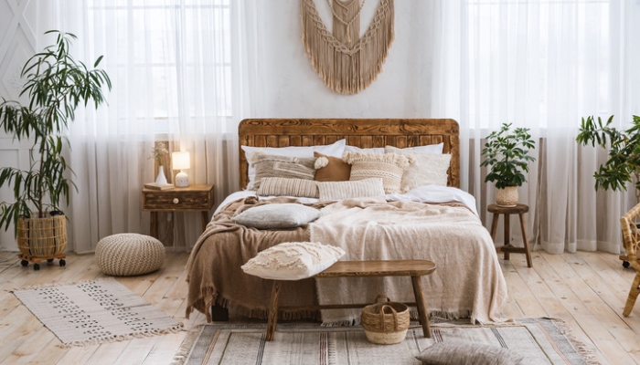 A neutral colored bedroom with bohemian accents and long, airy white curtains
