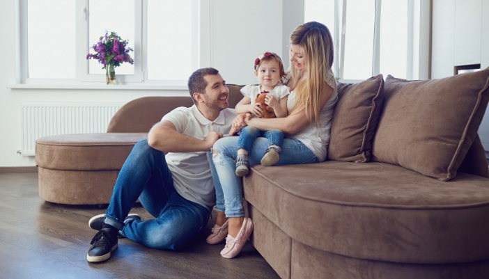 A young family laughing around a curved sofa chaise